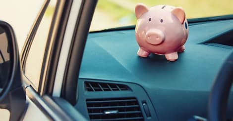 Pink piggy money box inside a car transportation. Saving money for vehicle purch