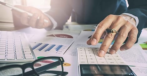 Businessman or accountant working on calculator to calculate business data concept. Accounting,investment advisor consulting situation on the financial report and planning a marketing plan at office.