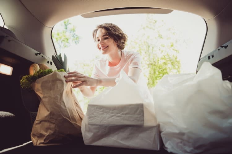 Photo of girl shopper put shopping bags in car trunk cabin ready ride drive home