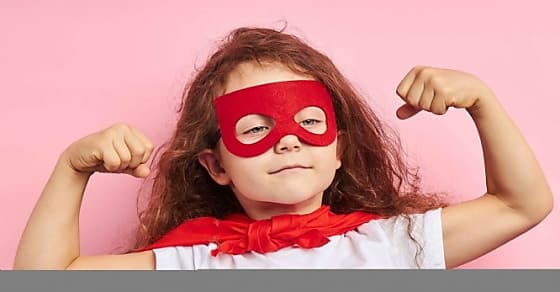 Beautiful little curly girl wearing red hero suit and mask showing how she is st