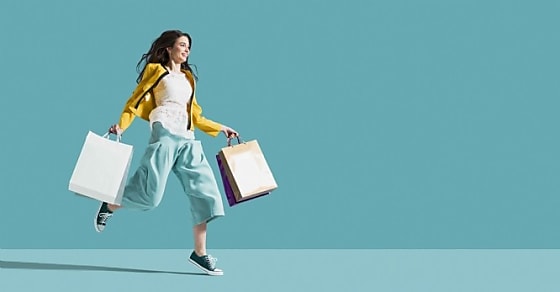 Cheerful happy woman enjoying shopping: she is carrying shopping bags and runnin
