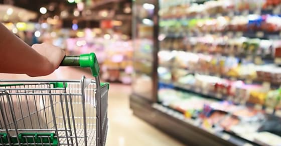 woman hand hold supermarket shopping cart with Abstract grocery store blurred de