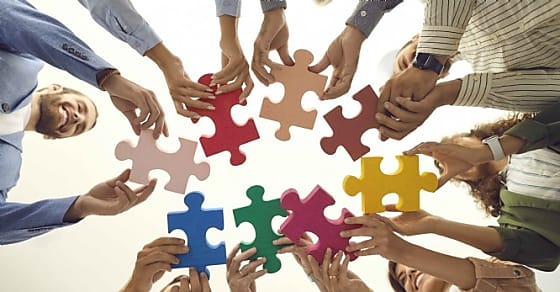 Group of young and mature people making circle of colorful jigsaw puzzle parts,