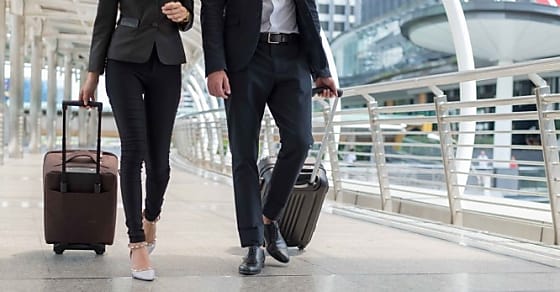business man and business woman walk together luggage on the public street, busi