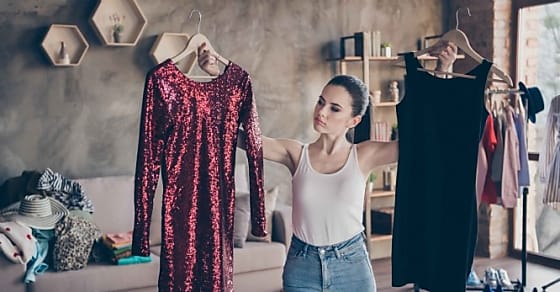 Portrait of her she nice attractive doubtful girl holding in hands hangers two new chic designer couture dress comparing preparing, party wear in modern loft industrial interior apartment