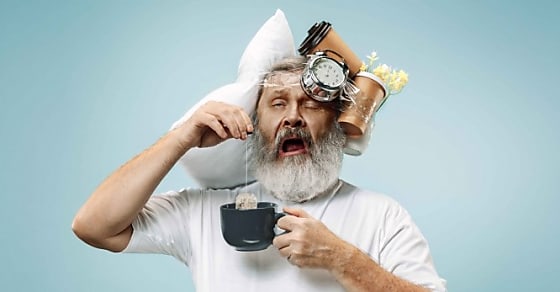 Surprised senior man drinking tea after sleeping at home or office having too much work. Bored businessman with pillow and hourglass. The busy, boring, worried, be late, concerned, sleep day, introuble concept