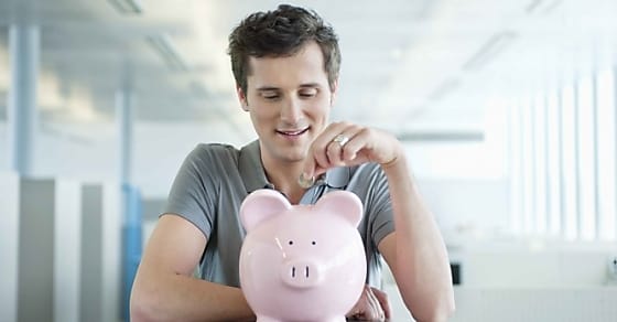 Businessman inserting a coin into a piggy bank
